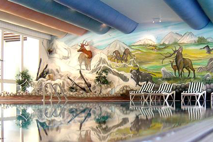 Het binnenzwembad van Hotel Winterberg Resort met een avontuurlijke muurschildering van een berglandschap met dieren.
