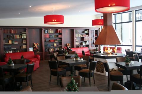 Het sfeervolle restaurant en de lounge van Hotel Winterberg Resort met een moderne open haard, rode lampen en comfortabele stoelen.