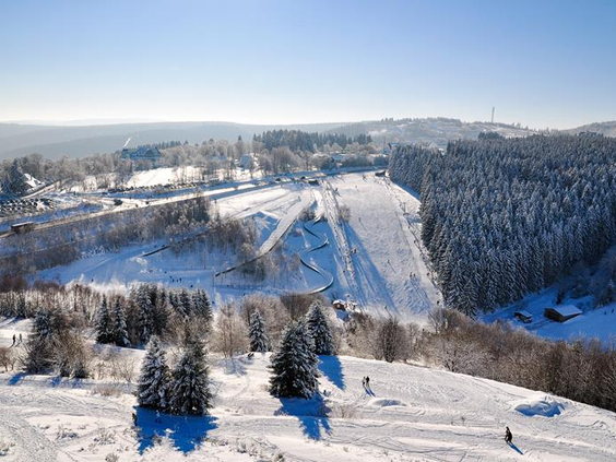 Een breed overzicht van het besneeuwde skigebied van Winterberg, met in de verte de beroemde St. Georg skischans.