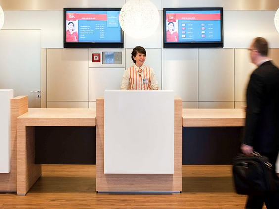 De moderne en vriendelijke receptie van het Ibis Hotel in Aken, waar gezinnen worden verwelkomd bij het inchecken.