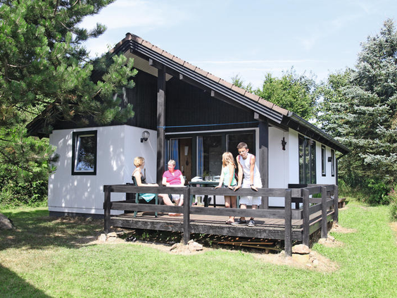 Een gezin ontspant op de houten veranda van hun vakantiehuis in Eifelpark Kronenburger See in de Duitse Eifel.