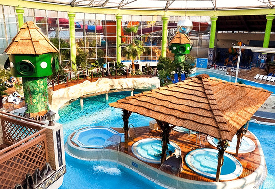 Overzicht van een subtropisch zwemparadijs (Aqua Mundo) met meerdere bubbelbaden, een stroomversnelling en tropische aankleding.