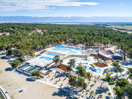 Luchtfoto van het uitgestrekte zwembadcomplex van Zaton Holiday Resort in Kroatië, omgeven door groene pijnbomen, een topkeuze voor een kindvriendelijke vakantie.