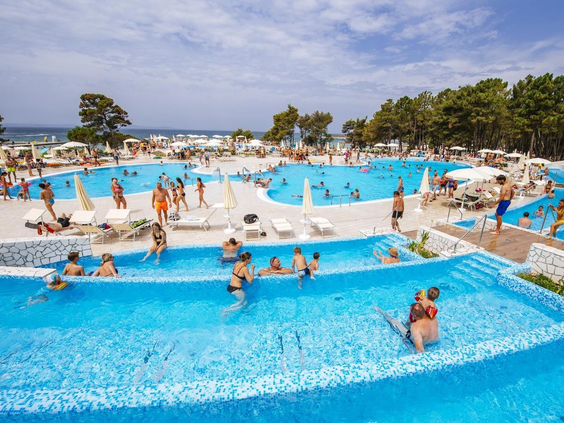 Gasten genieten van het grote, levendige zwembad met verschillende niveaus op een zonnige dag bij het kindvriendelijke Zaton Holiday Resort.