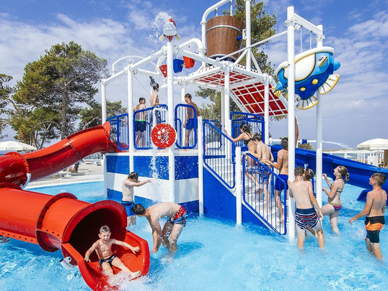 Kinderen spelen op een waterspeeltoestel met een rode glijbaan en sproeiers in het kinderbad van Zaton Holiday Resort, ideaal voor een gezinsvakantie.