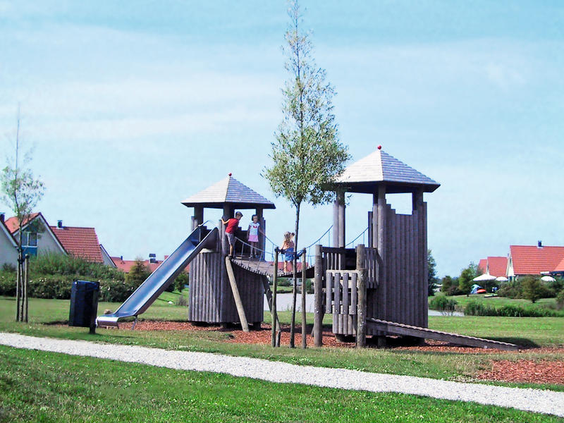 Kinderen spelen in de houten buitenspeeltuin met glijbaan en klimtorens op Vakantiepark Sandur in Emmen.