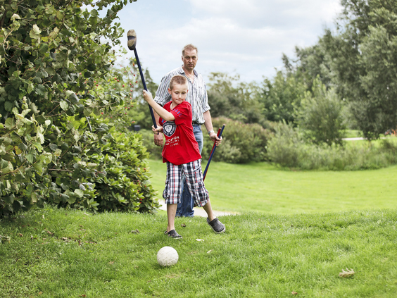 Een vader en zoon spelen samen een potje footgolf op een grasveld bij Vakantiepark Sandur.