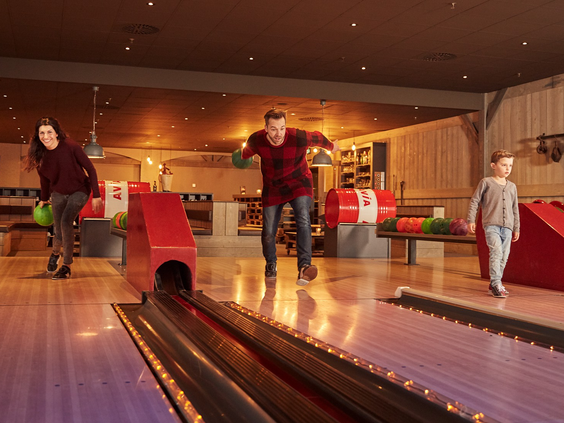 Een gezin is gezellig aan het bowlen op de bowlingbaan in het centrumgebouw van Vakantiepark Sandur.