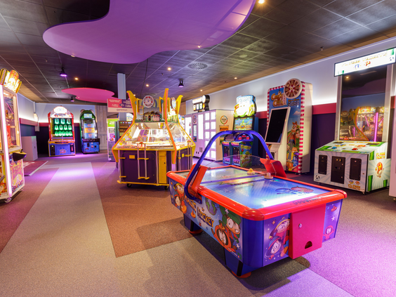 De kleurrijke arcadehal, de Game Zone, op Vakantiepark Sandur vol met spellen zoals airhockey en race games.