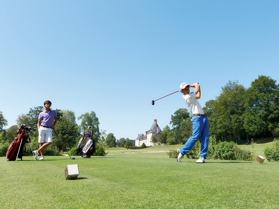 Twee mannen spelen golf op de prachtige, groene 18-holes golfbaan van Domaine des Ormes in Bretagne, Frankrijk.