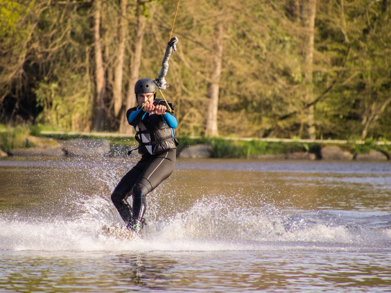 Een waterskiër maakt een scherpe bocht op het meer bij de waterskibaan van camping Domaine des Ormes.