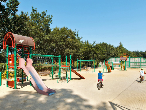 Zonnige buitenspeeltuin met zand, glijbaan en klimrekken op camping Domaine des Ormes, ideaal voor een kindvriendelijke vakantie in Frankrijk.