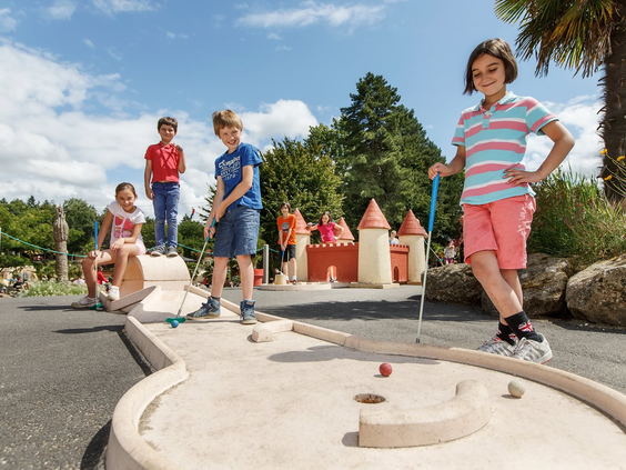 Kinderen spelen midgetgolf op de avontuurlijke minigolfbaan van de kindvriendelijke camping Domaine des Ormes in Dol-de-Bretagne.