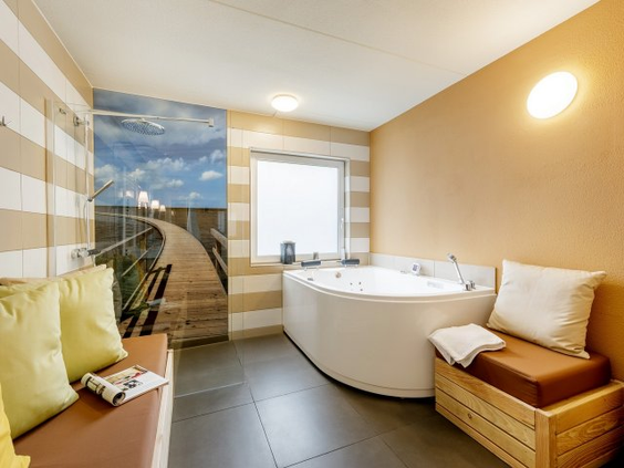 Luxe badkamer in een vakantiehuisje van Park Nordseeküste, met een groot hoekbubbelbad voor optimale ontspanning.