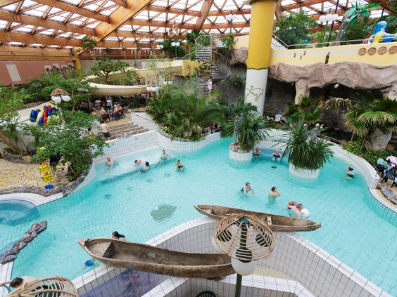 Overzicht van het subtropische zwemparadijs Aqua Mundo in Park Nordseeküste met diverse zwembaden, palmbomen en een glijbaan.