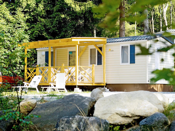 Een gezellige stacaravan met een houten veranda, gelegen tussen de rotsen en het groen op KNAUS Campingpark Lackenhäuser.