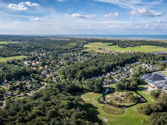 Luchtfoto van Kustpark Texel en de bosrijke omgeving van De Koog, met de Noordzee aan de horizon.