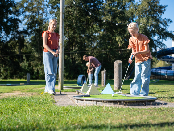 Gezin speelt een potje midgetgolf op de buitenbaan van Kustpark Texel.