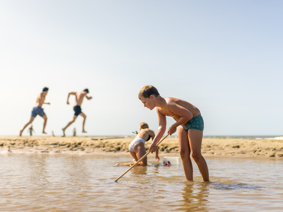 Kinderen spelen in het zand en de branding van de zee op het strand van Texel.
