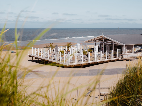 Sfeervol wit strandpaviljoen op het strand van Texel, gezien vanuit de duinen met uitzicht op zee.