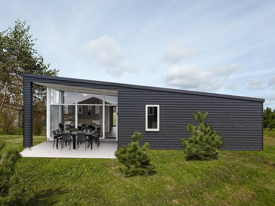 De buitenkant van een moderne Design Plus 6 vakantiewoning bij Lalandia Billund, met een ruim terras en veel groen.