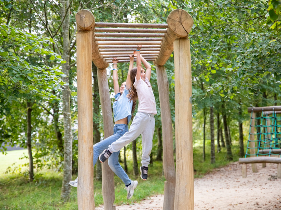 Kinderen die klimmen op een houten klimrek in een van de buitenspeeltuinen van vakantiepark Lalandia Billund.
