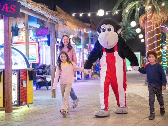 Een gezin dat op de foto gaat met de grote mascotte Monky Tonky in het overdekte centrum van Lalandia Billund.