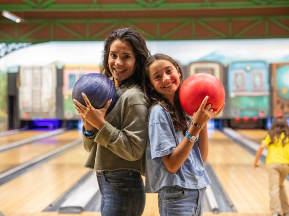 Twee lachende meiden met bowlingballen in hun handen op de bowlingbaan van Lalandia Billund.
