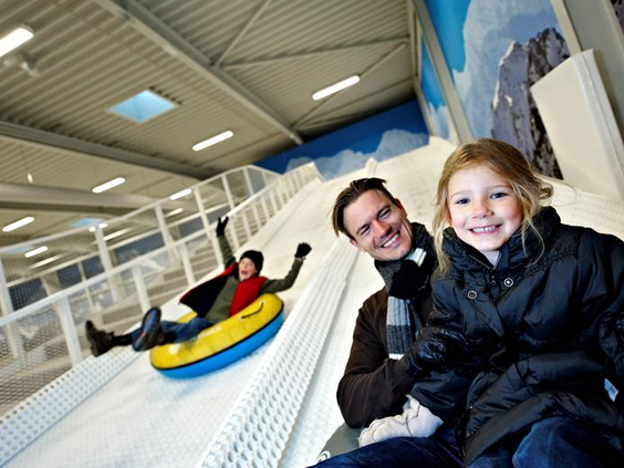 Een vader en dochter die plezier hebben met tubing van de indoor sneeuwhelling in Winter World, Lalandia.