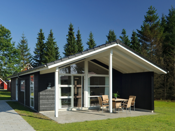 De buitenkant van een modern Classic Plus 4 vakantiehuis bij Lalandia Billund, gelegen tussen de bomen.