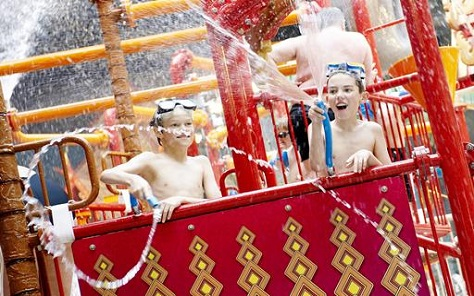 Kinderen met duikbrillen die een watergevecht houden met waterkanonnen in de waterspeeltuin van het Aquadome.