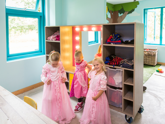 Drie meisjes, verkleed in roze prinsessenjurken, spelen in de kleurrijke verkleedhoek van de Bollo Club op kindvriendelijk vakantiepark Landal het Land van Bartje.