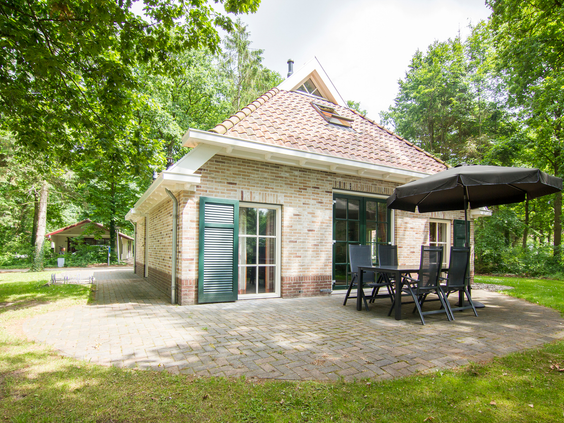 Een vrijstaande bungalow met een terras en tuinmeubilair, gelegen in het bos op het rustige vakantiepark Landal het Land van Bartje in Drenthe.