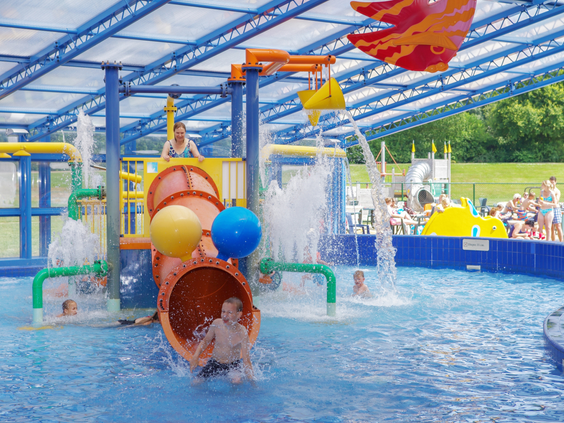 Jongen speelt in de waterspeeltuin met glijbaan en waterelementen in het openluchtzwembad op het kindvriendelijke vakantiepark Landal het Land van Bartje.