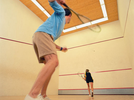 Een man en een vrouw spelen een fanatiek potje squash op een van de indoor squashbanen van Landal Aelderholt.