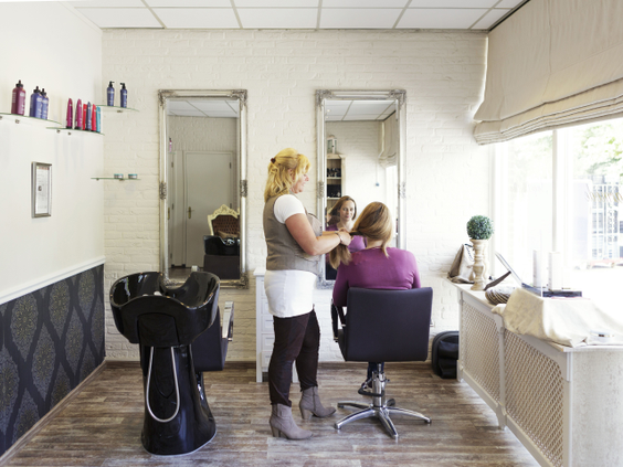 Een kapster behandelt het haar van een klant in de professionele kapsalon op vakantiepark Landal Aelderholt in Drenthe.