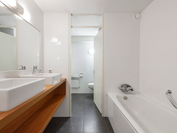 Moderne badkamer in een appartement van Landal Ameland State met dubbele wastafel, spiegel en een heerlijk ligbad om in te ontspannen.