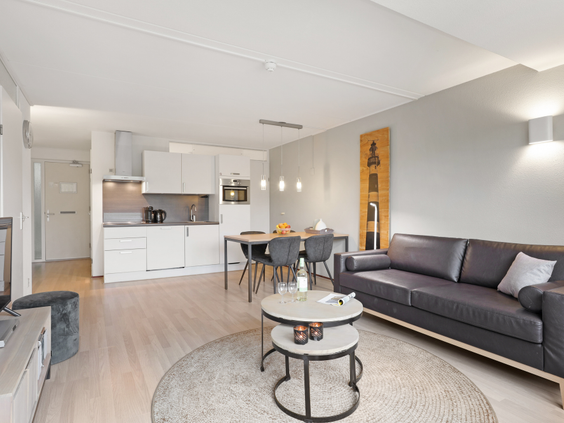 Stijlvolle en moderne woonkamer met open keuken in een appartement van Landal Ameland State, compleet met zithoek en eettafel.