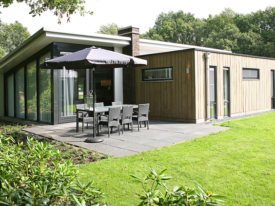Een moderne, duurzame bungalow met houten gevel en een ruim terras met tuinmeubilair op Landal Amerongse Berg.