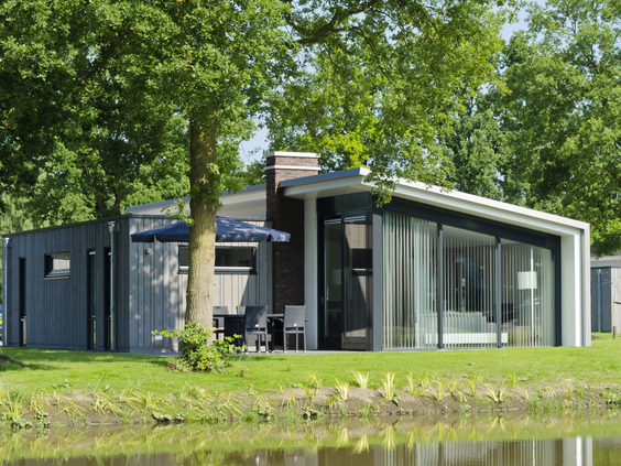 Een duurzame design bungalow met grote ramen, verscholen tussen de hoge bomen en aan het water op Landal Amerongse Berg.