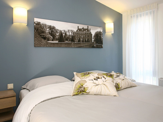 Een comfortabele tweepersoonsslaapkamer in een bungalow op Landal Amerongse Berg, met een opgemaakt bed en sfeerverlichting.