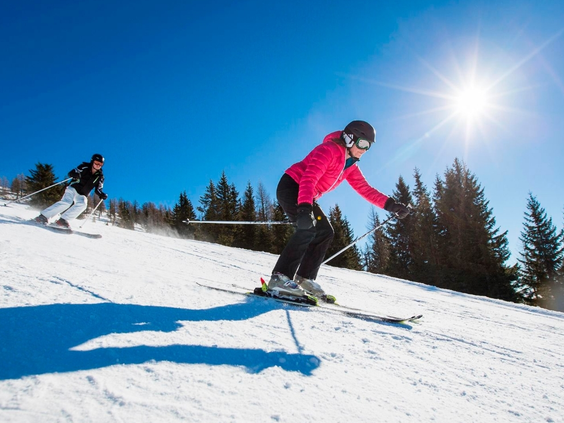 Een skiër maakt een bocht op een zonnige, besneeuwde piste in het skigebied van de Grote Arber.