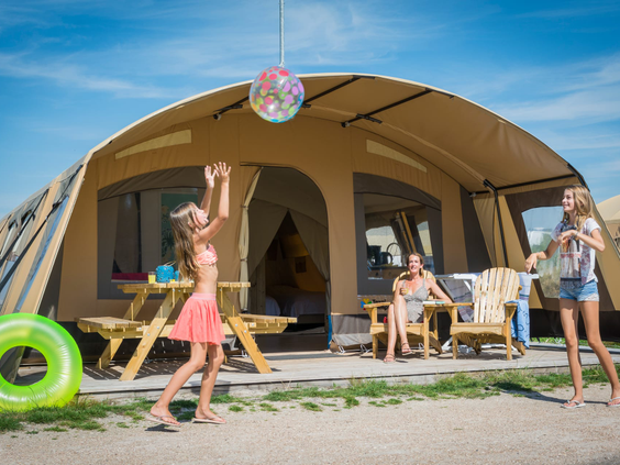 Gezin geniet bij een luxe safaritent op Landal Beach Park Texel, met spelende kinderen.