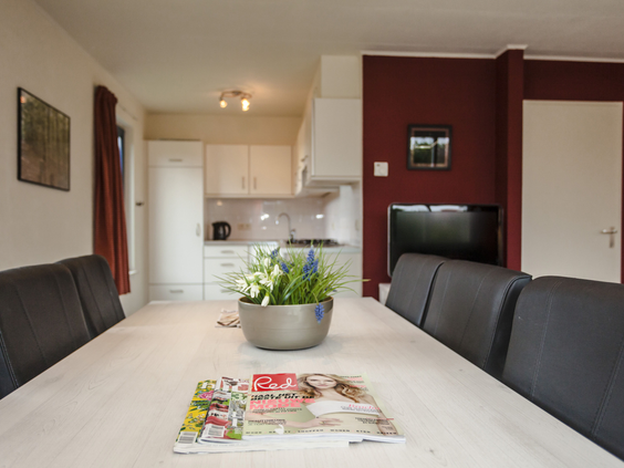 De gezellige eethoek met een lange tafel en de open keuken in een vakantievilla op Landal Beach Park Texel.