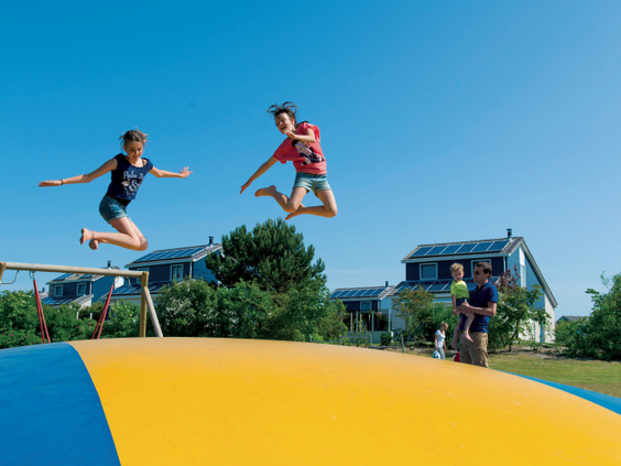 Kinderen maken hoge sprongen op de grote airtrampoline op Landal Beach Park Texel.