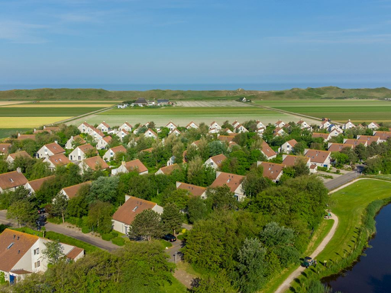 Luchtfoto van Landal Beach Resort Ooghdyne, met de vakantiehuizen tussen het groen en de Noordzeekust op de achtergrond.