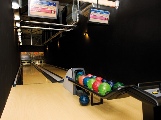 De moderne bowlingbaan van Landal Beach Resort Ooghdyne met kleurrijke bowlingballen en digitale scoreborden.