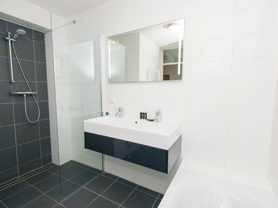 De moderne en luxe badkamer in een vakantievilla, voorzien van een ruime inloopdouche en een dubbele wastafel.
