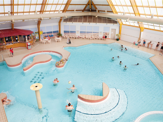 Overzicht van het ruime, overdekte zwemparadijs van Landal Beach Resort Ooghdyne met recreatiebad en spelende gasten.