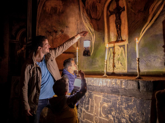 Bezoekers met een lantaarn bekijken de eeuwenoude houtskooltekeningen op de mergelwanden in een van de grotten van Valkenburg.